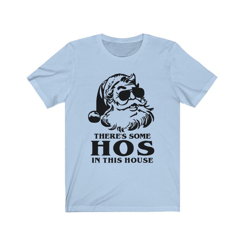 Pu&ograve; includere: T-shirt azzurra con una grafica nera di Babbo Natale con occhiali da sole. Il testo "THERE'S SOME HOS IN THIS HOUSE" &egrave; stampato sotto la grafica di Babbo Natale in un carattere grassetto senza grazie. La maglietta &egrave; realizzata in un materiale morbido.