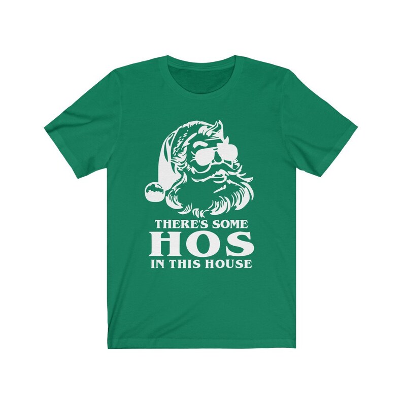 Pu&ograve; includere: T-shirt verde con grafica bianca di Babbo Natale con occhiali da sole e barba. Il testo "THERE'S SOME HOS IN THIS HOUSE" &egrave; stampato sotto. Un design divertente e festivo.
