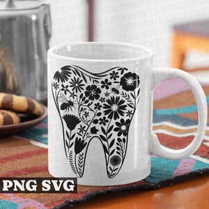 May include: White ceramic mug with a black silhouette of a tooth surrounded by flowers and bees. The mug has a black handle.