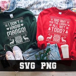 May include: Two Christmas-themed sweatshirts, one green and one red, with white text. The green sweatshirt says "I DON'T KNOW MARGO!" and the red one says "AND WHY IS THE CARPET ALL WET TODD?". The image also includes jeans, shoes, and holiday decorations.