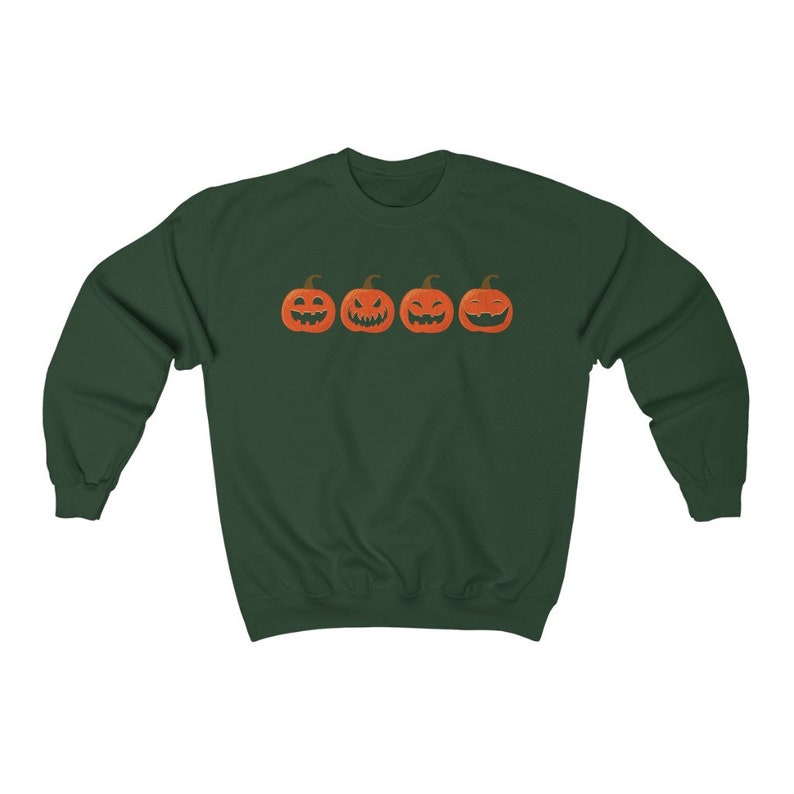 K&ouml;nnte beinhalten: Ein dunkelgr&uuml;nes Sweatshirt mit vier orangefarbenen K&uuml;rbisgesichtern mit unterschiedlichen Schnitzereien. Die K&uuml;rbisse sind horizontal angeordnet. Das Sweatshirt hat einen Rundhalsausschnitt und lange &Auml;rmel, ideal f&uuml;r Halloween.