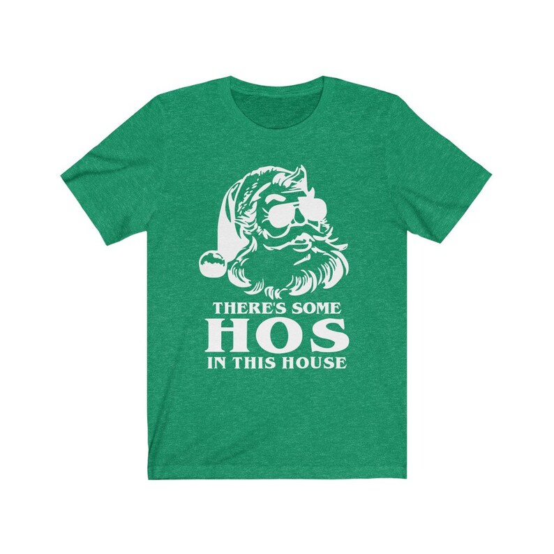 Pu&ograve; includere: T-shirt verde con grafica bianca di Babbo Natale con occhiali da sole e barba. Il testo "THERE'S SOME HOS IN THIS HOUSE" &egrave; stampato in bianco sotto. La maglietta &egrave; girocollo.