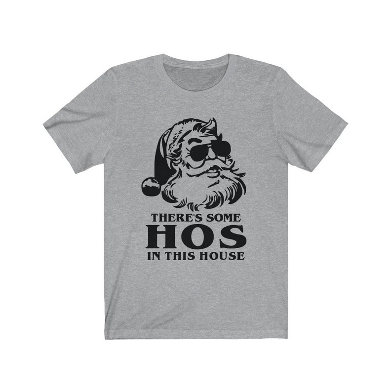Pu&ograve; includere: T-shirt grigia con grafica nera di Babbo Natale con occhiali da sole. Il testo "THERE'S SOME HOS IN THIS HOUSE" &egrave; stampato sotto. La maglietta ha maniche corte e girocollo. Il design &egrave; umoristico.