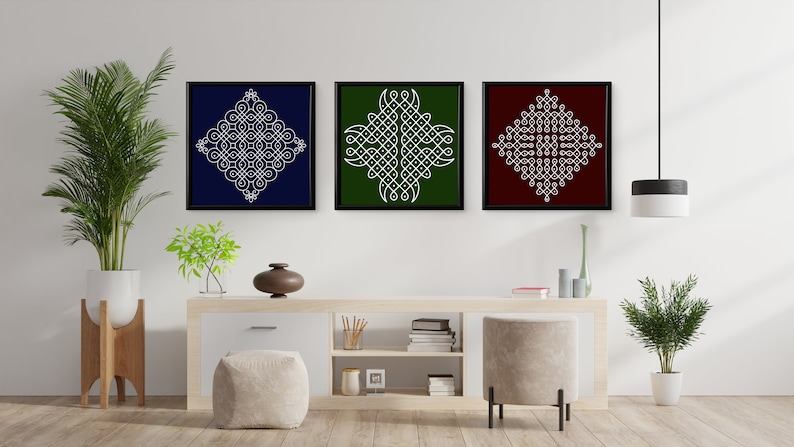 May include: Three framed prints with white geometric designs on different colored backgrounds. The prints are hanging on a white wall above a wooden shelf with books and decorative items.