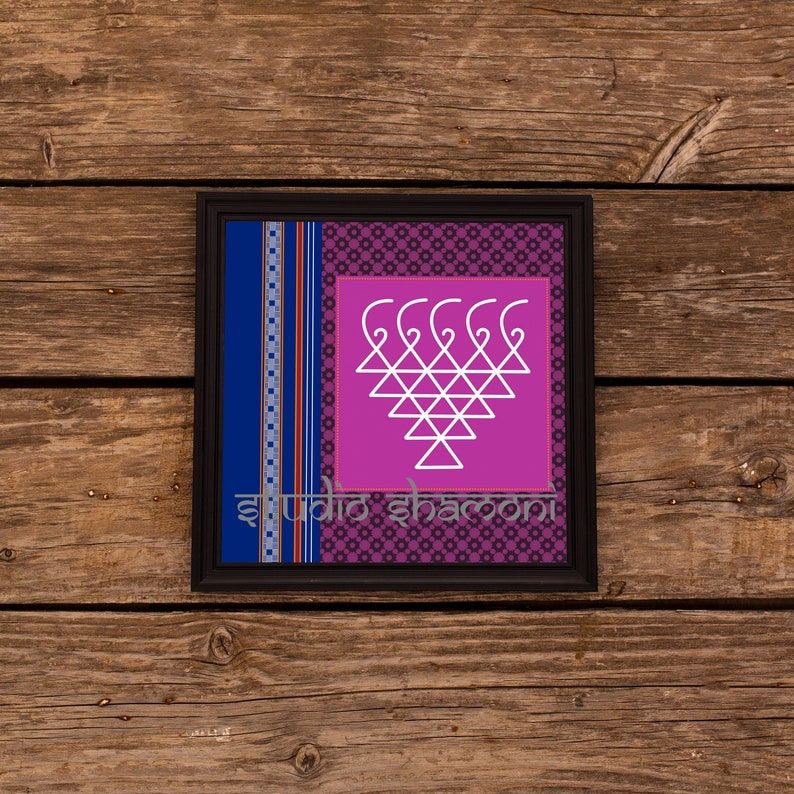 Op de afbeelding: Een ingelijst drukwerk met een roze achtergrond en een wit geometrisch ontwerp. Het ontwerp is een gestileerde hartvorm met een reeks gebogen lijnen aan de bovenkant. De lijst is zwart met een blauwe en witte gepatroneerde rand. De tekst "studio shamoni" is onderaan het drukwerk gedrukt.