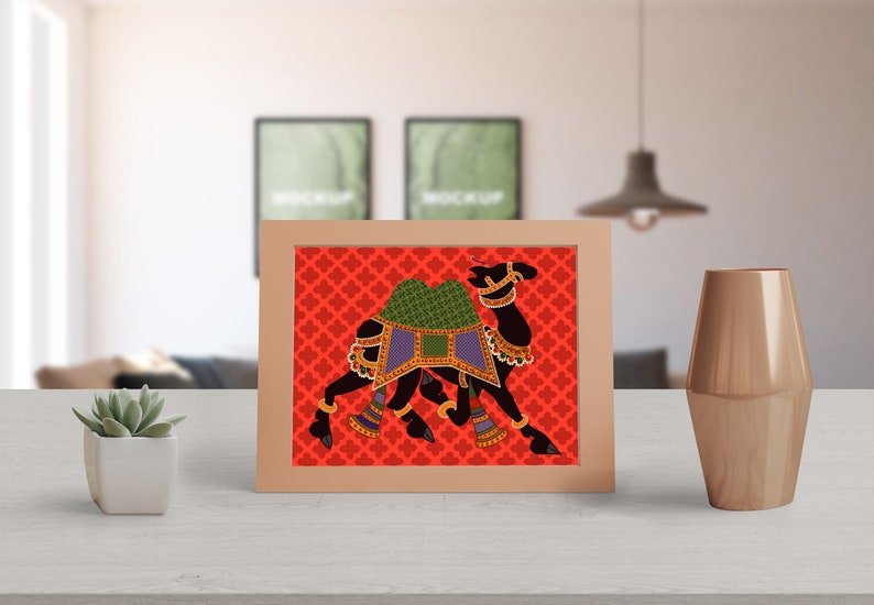 May include: A framed print of a black camel with colorful decorations on a red background with a repeating pattern. The camel is walking to the right.