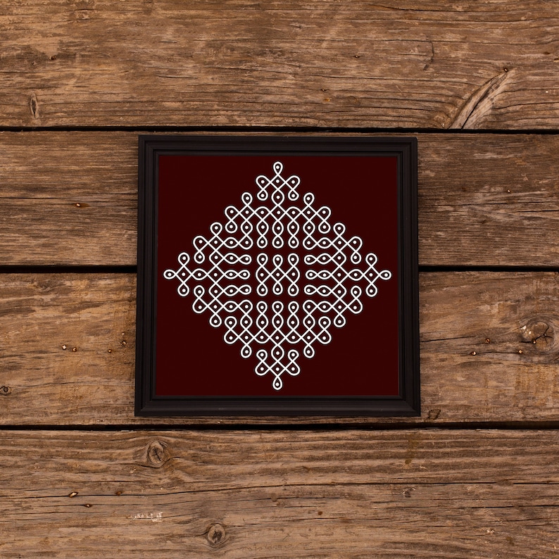 May include: A framed white geometric design on a maroon background. The design is a traditional Indian rangoli pattern.