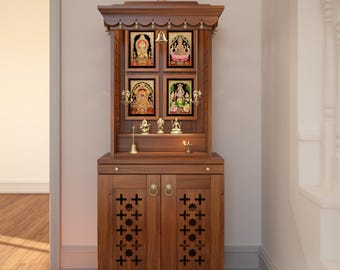 May include: A brown wooden home temple cabinet featuring a tiered roof with a central finial and hanging bells. The upper section displays four framed religious images and small brass idols. The base includes two doors with cross-shaped cutouts.