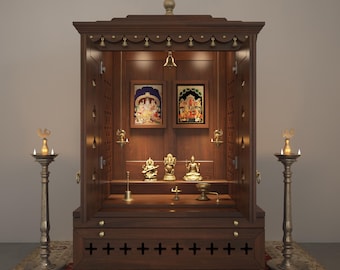May include: A dark brown wooden home temple cabinet featuring two framed religious prints, three small brass deity statues, and a hanging bell. The structure includes a base drawer with cross-shaped cutouts and two tall brass floor lamps.