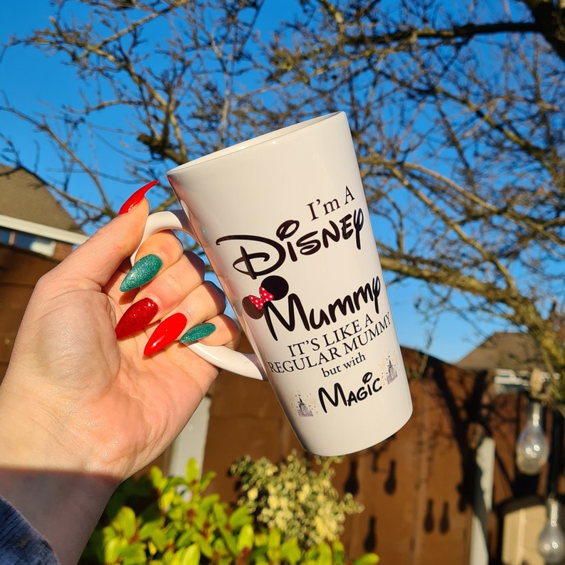 May include: White ceramic mug with a black and red design that says "I'm a Disney Mummy. It's like a regular mummy but with magic."