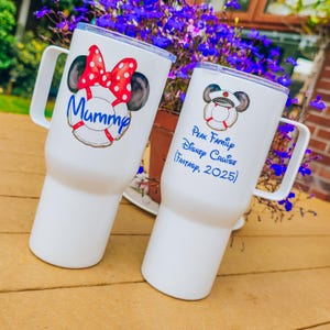 May include: Two white stainless steel tumblers with handles and clear lids. The left tumbler features a Minnie Mouse-inspired graphic with a red polka dot bow and the text Mummy. The right tumbler displays a captain hat graphic and the text Peak Family Disney Cruise (Fantasy, 2025) in blue script.