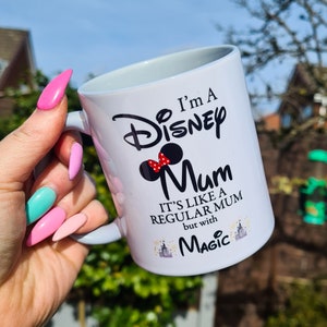 May include: White ceramic mug with a black and red design that says "I'm a Disney Mum. It's like a regular mum but with magic." The design includes a Mickey Mouse head with a red bow.