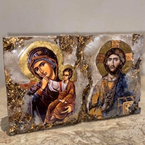 May include: A religious icon depicting the Virgin Mary holding a baby Jesus, with a gold background and a decorative frame. The icon is painted in a traditional style with vibrant colors.
