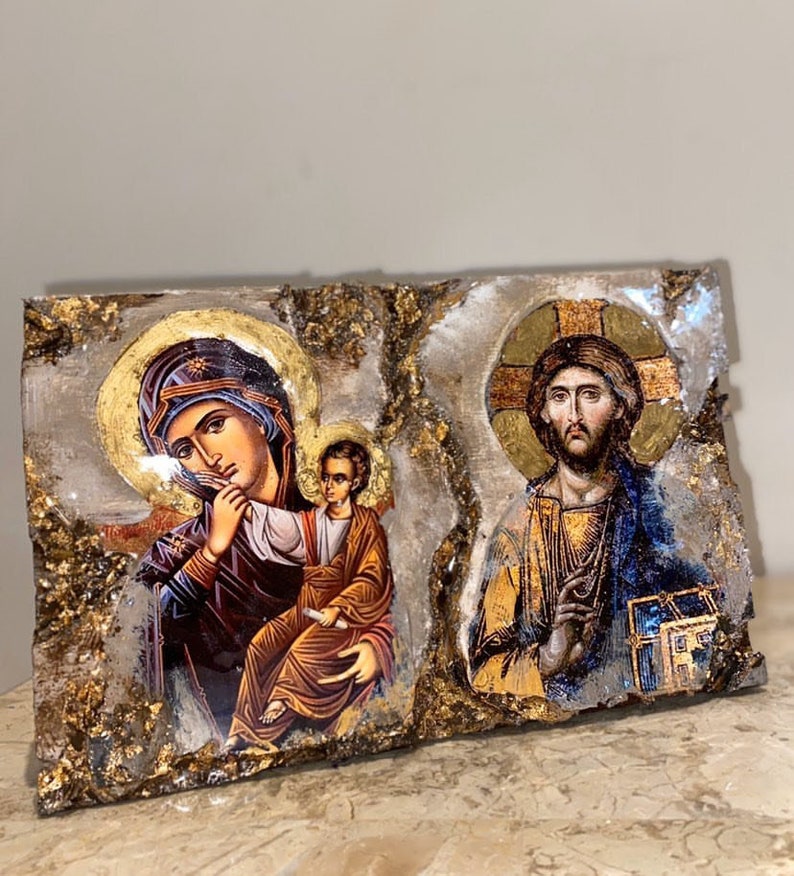 May include: A wooden plaque with a gold background and two religious icons. The left icon depicts the Virgin Mary holding a baby Jesus. The right icon depicts Jesus Christ with a halo and a cross behind him.