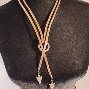 May include: A brown leather necklace with a silver circle pendant and two arrowhead charms.