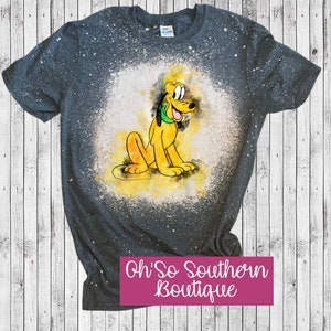 May include: A gray t-shirt with a bleach-splattered design featuring a cartoon image of Pluto, a yellow dog with a green collar. The text "Oh' So Southern Boutique" is printed in pink at the bottom of the shirt.