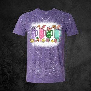 May include: A white ceramic mug with a black handle and the text "But First, Coffee" in a bold, black font. The mug is set against a blurred background, suggesting a cozy setting. The mug appears to be approximately 4 inches tall.