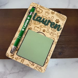 May include: A wooden notepad holder with a green notepad and a green pen. The holder is engraved with pet-themed icons and the name "Lauren" in green. The pen has the name "Lauren" printed on it.