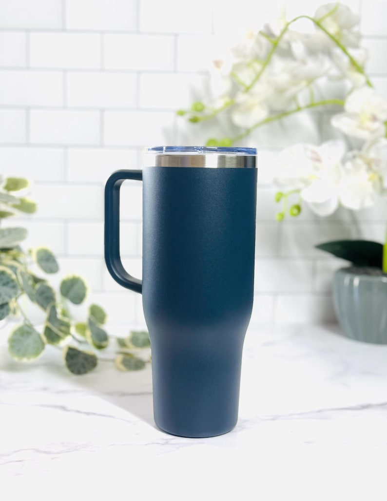 Puede incluir: Un vaso t&eacute;rmico azul marino con asa y tapa transparente. El borde y el asa de acero inoxidable contrastan con el acabado mate. Dise&ntilde;ado para mantener las bebidas calientes o fr&iacute;as.