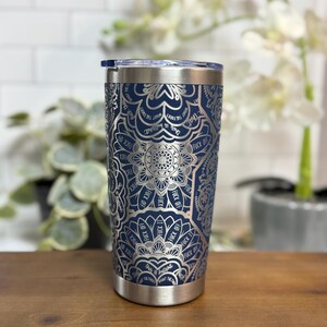 Puede incluir: Un vaso de acero inoxidable azul marino con un dise&ntilde;o de mandala plateado. El dise&ntilde;o incluye las palabras "FUCK OFF" y "this is bullshit". El vaso tiene un borde plateado y una tapa transparente.