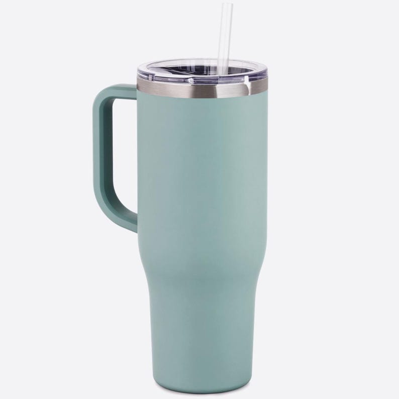 Puede incluir: Una taza de cer&aacute;mica blanca con un asa negra y el texto "But First, Coffee" en negro, con una fuente de estilo manuscrito. La taza est&aacute; sobre una superficie blanca.