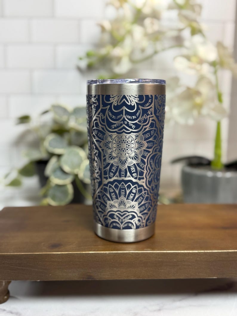 Puede incluir: Un vaso de acero inoxidable azul marino con un dise&ntilde;o de mandala plateado. El dise&ntilde;o incluye la frase "This is what the fuck I want" y "Fuck Off". El vaso tiene un borde y una base plateados.