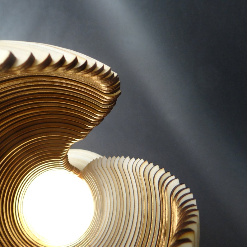 May include: A wooden lampshade with a spiral design, featuring a light source in the center. The lampshade is made of thin, layered wood strips, creating a unique and intricate pattern.