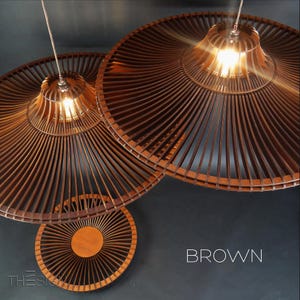 May include: Two brown wooden pendant lights with a woven design. The lights are hanging from the ceiling and are illuminated. The word "BROWN" is written in white letters on a dark background.