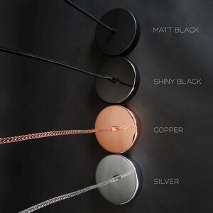May include: Four round metal ceiling canopy options for pendant lights. The canopies are shown in matt black, shiny black, copper, and silver.