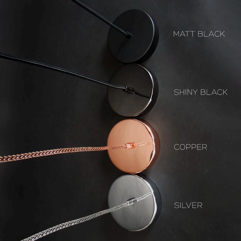 May include: Four round metal ceiling canopy options for pendant lights. The canopies are shown in matt black, shiny black, copper, and silver.