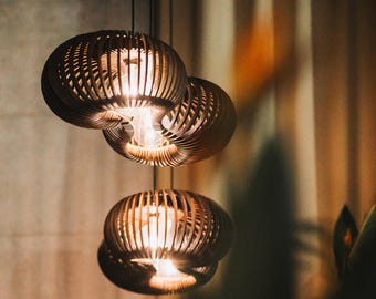May include: Three wooden pendant lights with a woven design. The lights are hanging from the ceiling and are illuminated with warm white light bulbs.