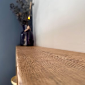 May include: A close-up of a light brown wooden shelf with a natural wood grain pattern. The shelf is empty and appears to be part of a larger piece of furniture.