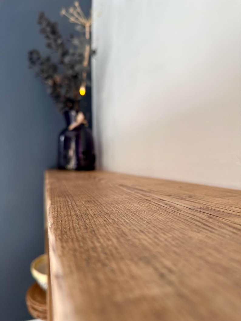 May include: A close-up of a light brown wooden shelf with a natural wood grain pattern. The shelf is empty and appears to be part of a larger piece of furniture.