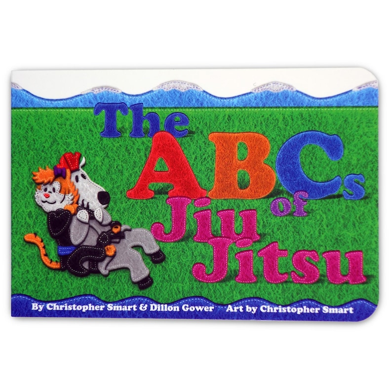 May include: A colorful book cover with the title "The ABCs of Jiu Jitsu" in large, colorful letters. The cover features a cartoon illustration of a cat and a dog in a jiu jitsu pose on a green background.