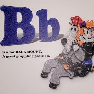 May include: A blue felt letter B with a stitched border. The letter is next to a smaller blue felt letter b. A cartoon illustration of a tiger in a black gi with a white dog on its back. The text below the letters reads "B is for BACK MOUNT. A great grappling position."
