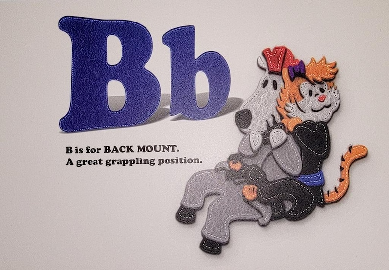 May include: A blue felt letter B with a stitched border. The letter is next to a smaller blue felt letter b. A cartoon illustration of a tiger in a black gi with a white dog on its back. The text below the letters reads "B is for BACK MOUNT. A great grappling position."