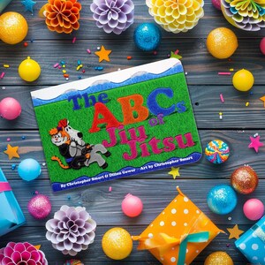 May include: A colorful book titled "The ABC's of Jiu Jitsu" by Christopher Stuart & Damon Garner. The book cover features a green background with a cartoon illustration of a person in a blue gi practicing jiu jitsu.