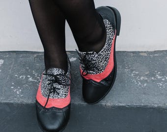 Zapatos Oxford de piel negra con detalles de ante rosa y estampado de leopardo.
