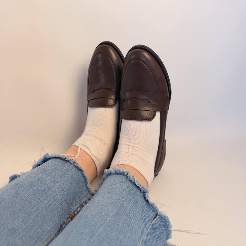 The handcrafted loafers appear comfortable, versatile, and easy to style for everyday wear, office outfits, university looks, travel wardrobes, and smart casual occasions. The low-profile silhouette and flat sole emphasize comfort while maintaining a polished refined appearance. Visible stitching around the edges highlights careful craftsmanship and handmade construction.