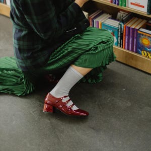 These burgundy Mary Jane heels aren’t just shoes — they’re a mood. Made from glossy patent leather with triple straps and a comfy block heel, they channel vintage charm with modern edge. Perfect for nights out, gallery strolls, or simply being that girl.