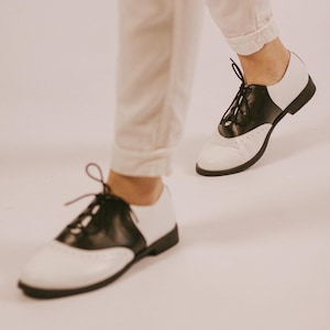These black and white oxford shoes are made for those who love timeless style with a bold edge.
A perfect balance between masculine structure and feminine elegance, this design creates a strong, confident silhouette while staying minimal and effortless. The contrast of black and white leather makes them stand out without being loud — a statement piece you can wear every day.
Whether styled with trousers, denim, or a dress — they instantly elevate your look.