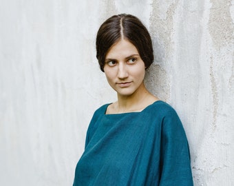Op de afbeelding: Een donkergroenblauw tuniekjurk met een vierkante halslijn en wijde driekwartmouwen. Het kledingstuk heeft een los, vloeiend silhouet en bevat zijzakken die in de naden van de stof zijn verwerkt, wat zorgt voor een functioneel ontwerp.