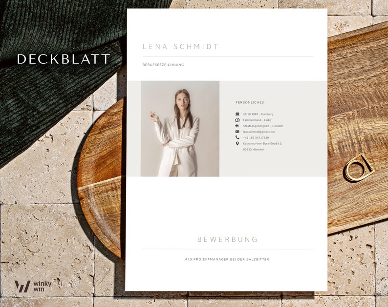 May include: A resume template with the name "LENA SCHMIDT" at the top. The document includes personal details and the word "BEWERBUNG" at the bottom. The word "DECKBLATT" is in the upper left corner. The resume is on a wooden surface.