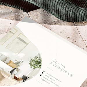 Pode incluir: Um cart&atilde;o de visita com o nome "OLIVIA SCHNEIDER" impresso em uma fonte minimalista. O cart&atilde;o apresenta informa&ccedil;&otilde;es de contato, incluindo um endere&ccedil;o de e-mail e um n&uacute;mero de telefone. O fundo inclui um vislumbre de um design de interiores moderno e um tecido verde.