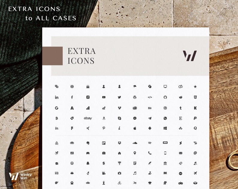May include: A white sheet with the text "EXTRA ICONS" and a collection of small, black icons. The icons include social media logos, symbols, and other graphic elements. The sheet is on a wooden surface.