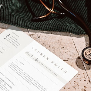 May include: A white CV with a black and white heartbeat graphic and the text "LAUREN SMITH REGISTERED NURSE". The CV is on a beige surface with a stethoscope.