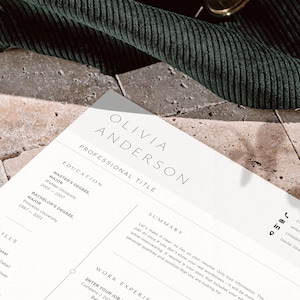 May include: A resume with the name "OLIVIA ANDERSON" at the top. The resume includes sections for education, skills, and work experience. The resume is on a light-colored paper with a dark green fabric in the background.