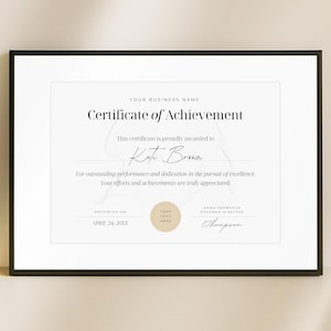 Op de afbeelding: Een ingelijst certificaat van prestatie met zwarte randen. Het certificaat heeft een witte achtergrond met elegante tekst, waaronder "Certificate of Achievement" en de naam van de ontvanger, "Kate Brown". Een logo en handtekening zijn ook aanwezig.
