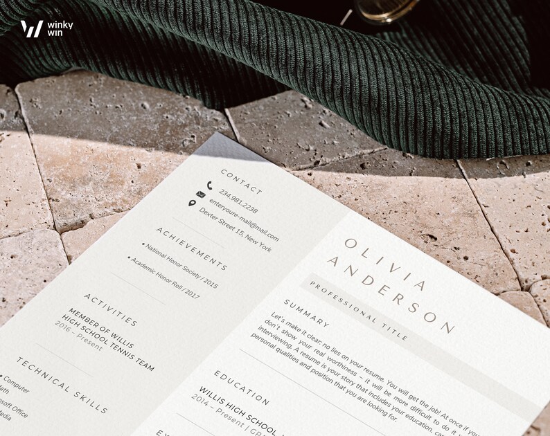 May include: A resume with the name Olivia Anderson, contact information, achievements, activities, technical skills, and education. The resume is on a light beige surface with a dark green corduroy fabric in the background.