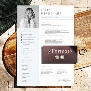 Może przedstawiać: Profesjonalny szablon CV z fotografią kobiety, podsumowaniem zawodowym i listą kwalifikacji. CV jest na jasnoniebieskim tle z czarnym tekstem. Mała karta z napisem "2 Formate" znajduje się na CV. CV leży na drewnianej tacy.